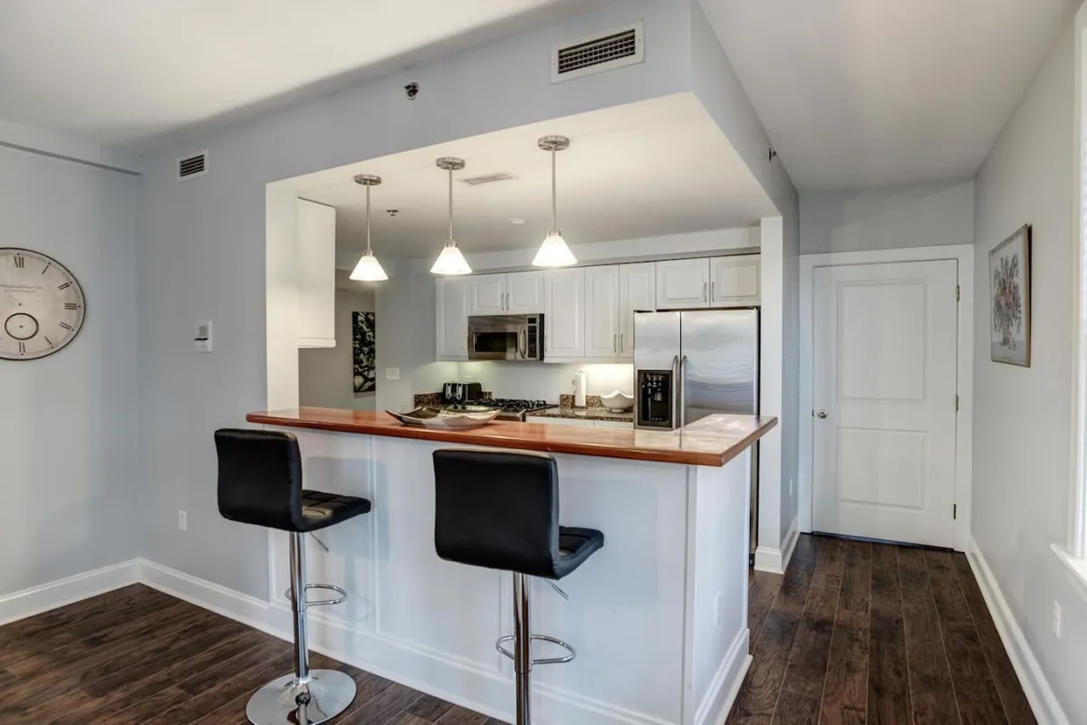 A modern, comfortable open-plan kitchen and bar area with sleek appliances, bar counter, and stools. The layout is ideal for entertaining guests, sharing meals, or enjoying drinks with friends after a day exploring Asheville.