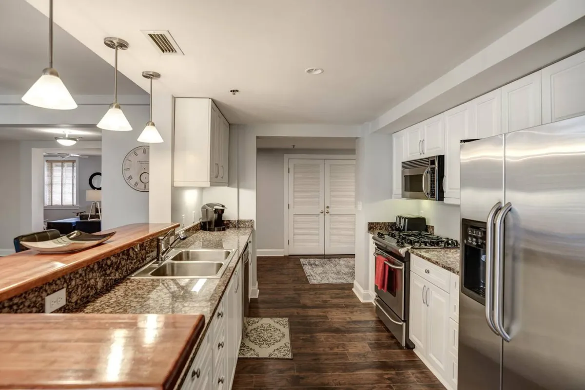 Focusing on the culinary zone, this image highlights granite countertops, stainless steel appliances, and a central kitchen island. The setup is ideal for cooking, socializing, and entertaining, reflecting an updated kitchen that blends functionality with style. The inviting, organized space is perfect for both everyday meals and festive occasions.