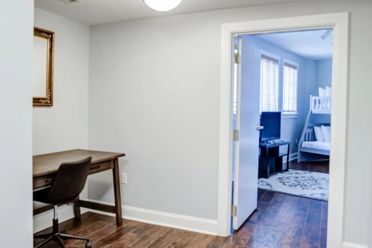 A versatile bonus room featuring a bunk bed, a desk with chair, and an open doorway. The space feels calm and functional, ideal for children to play or relax after a busy day, and flexible enough for quiet study or downtime.