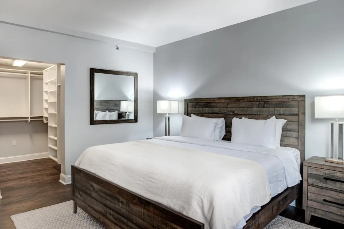 A king bedroom featuring a spacious bed flanked by nightstands, a closet, and a large mirror. The room exudes a peaceful atmosphere, suggesting comfort and privacy ideal for couples or parents seeking a restful retreat.