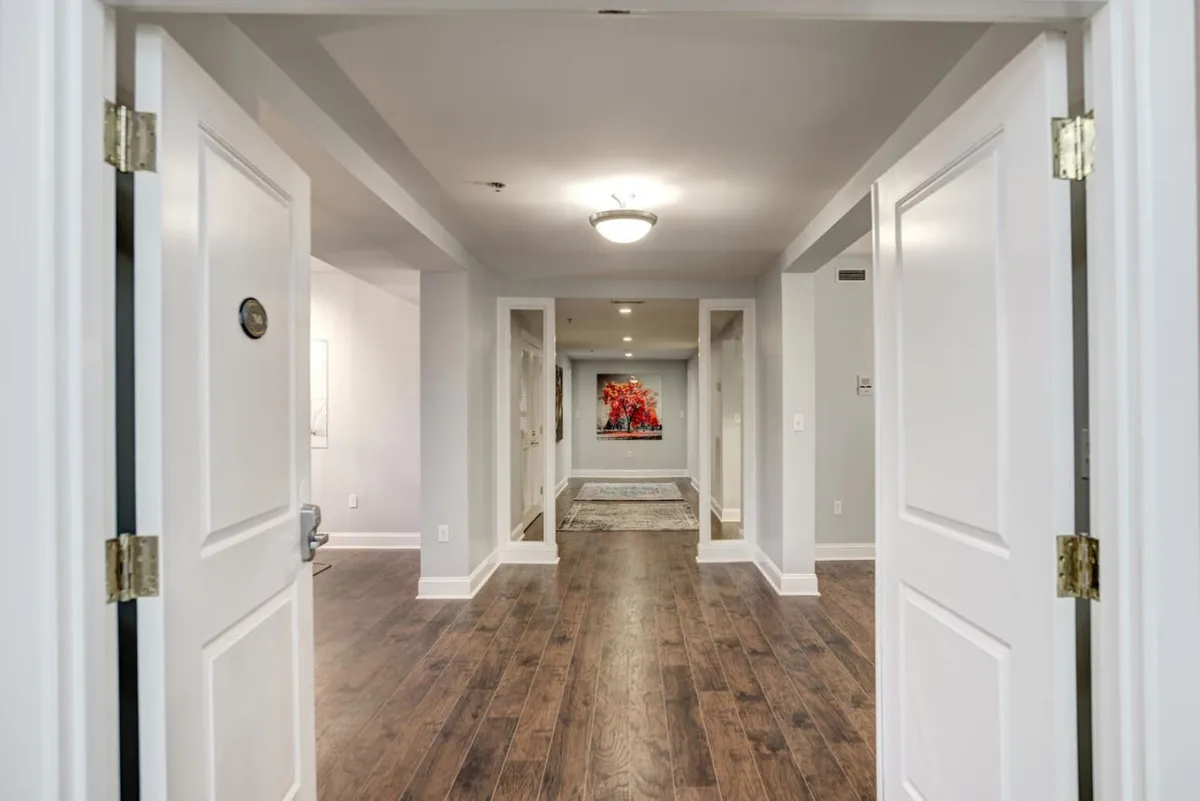 This image depicts open doorways, elegant artwork, and warm wooden flooring, setting a welcoming, historic tone as guests first enter the living space. The inviting mood and visible architectural details evoke a sense of arrival and anticipation for shared experiences.